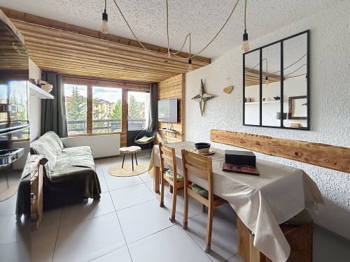 Appartement ski-in lumineux aux Tanières à Montgenèvre avec poutres en bois, table de salle à manger, canapé, balcon avec vue montagne et