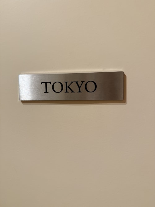 Plaque nominative en argent brossé gravée TOKYO sur mur beige à la maison d'hôtes Le Montreal à Montréal du Gers