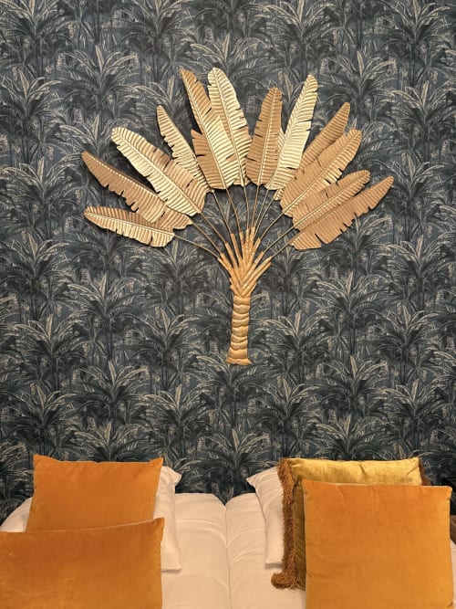 Décoration murale en feuille de palmier doré au-dessus du lit avec coussins orangés dans la chambre PAMPA du gîte Le Montreal, Montréal du Gers