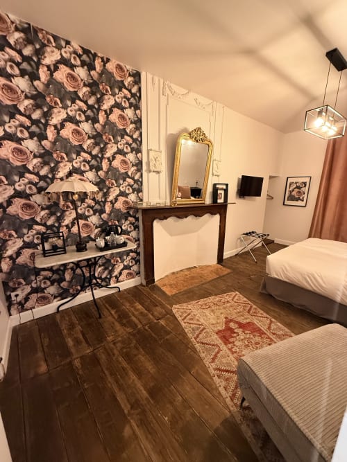 Chambre élégante au gîte Le Montreal avec papier peint fleuri, cheminée et parquet