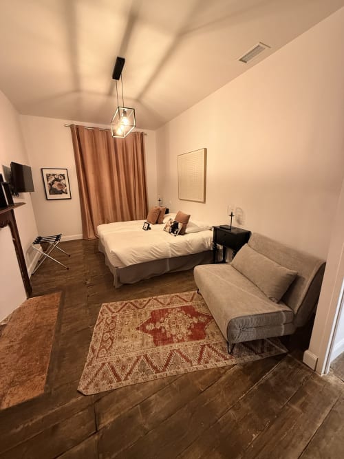 Chambre douillette au Le Montreal B&B à Montréal du Gers avec lit, canapé, planchers en bois dur et luminaires suspendus modernes