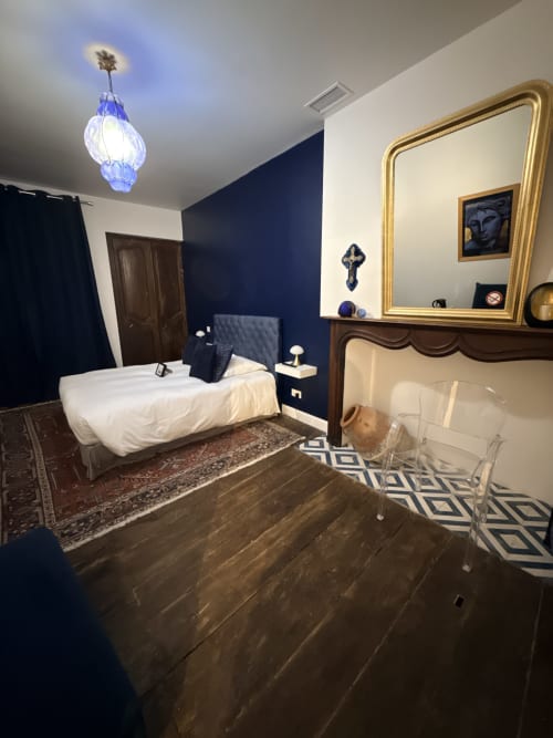 Chambre élégante au B&B Le Montreal à Montréal du Gers avec murs bleu marine, miroir doré et luminaire suspendu bleu moderne
