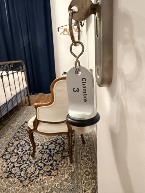 Porte-clés de la chambre 3 au gîte Le Montreal à Montréal du Gers, France, avec chaise en bois et tapis à motifs