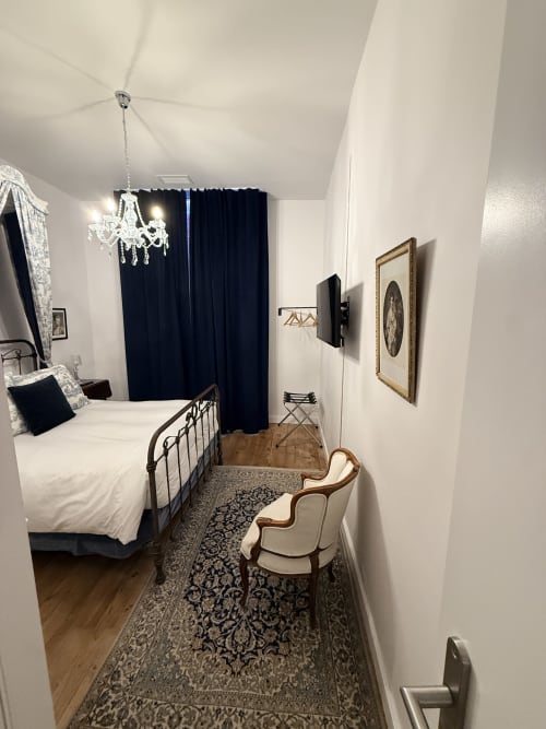 Chambre élégante au gîte Le Montreal à Montréal du Gers avec lit en fer forgé, rideaux sombres, lustre et décor classique