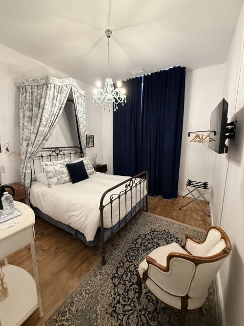 Chambre élégante du gîte Le Montreal avec lit à baldaquin, lustre en cristal et rideaux bleu foncé