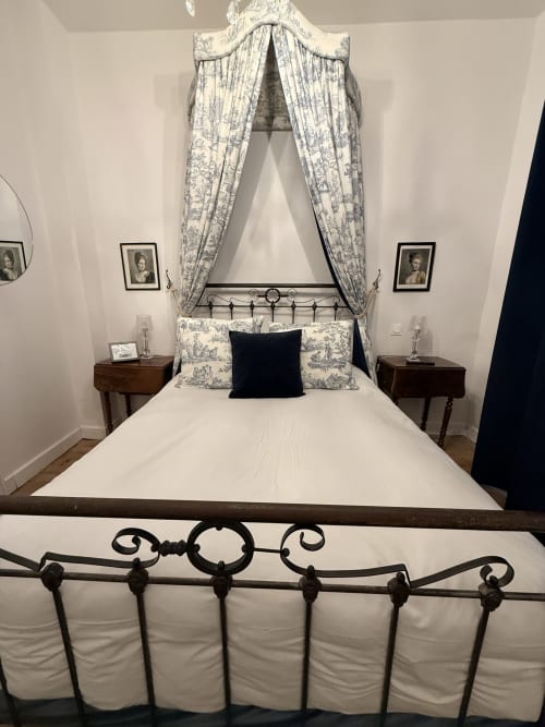 Chambre élégante avec lit en fer forgé orné, rideaux baldaquin bleu toile, et mobilier d'époque au gîte Le Montreal à Montréal
