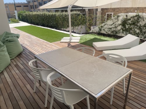 Modern terrace with dining table, lounge chairs, and private garden at Like at Home Palau apartment