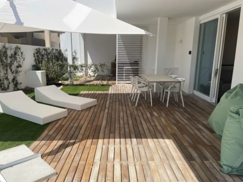Modern garden patio at Like at Home Palau with wooden deck, dining table, lounge chairs, and private garden area