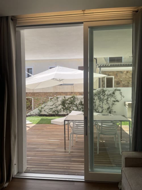 Garden view from Like at Home Palau apartment with wooden deck, lawn, white umbrella, and dining area overlooking private