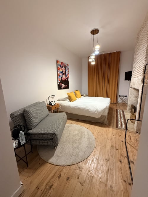 Chambre moderne au gîte Le Montreal à Montréal du Gers avec lit, coin séjour, parquet et luminaires suspendus