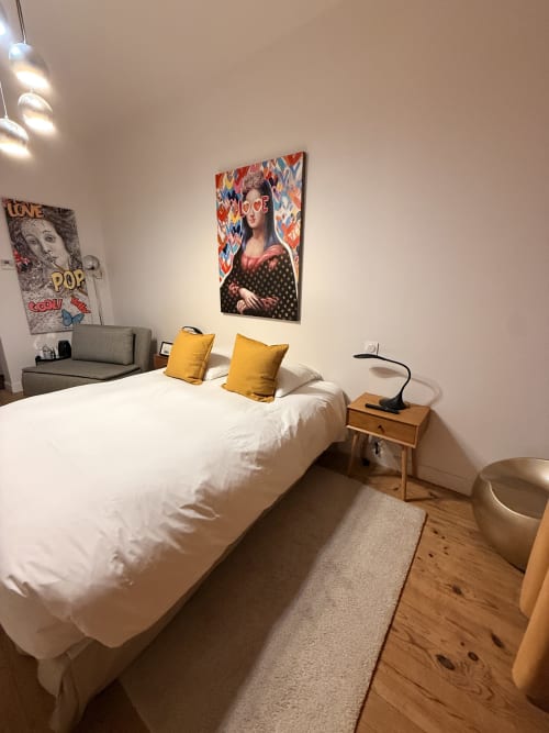 Chambre moderne du Le Montreal BnB avec lit blanc, coussins jaunes, décor pop art et table de nuit en bois, Montréal du Gers