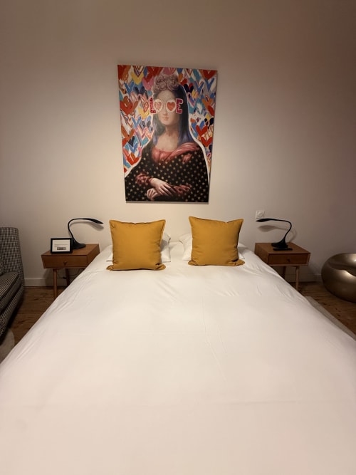 Chambre moderne à La Montreal BnB avec lit blanc, coussins dorés et pop art coloré au-dessus des tables de nuit à Montréal du Gers