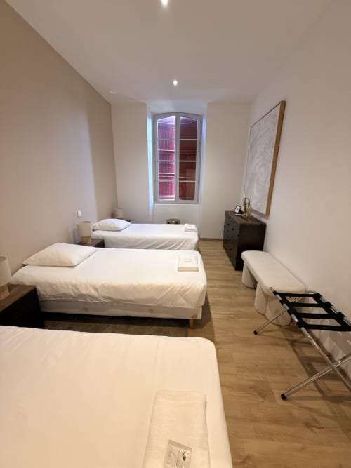 Chambre triple du Le Montreal B&B avec parquets, lits blancs et vue sur la ville de Montréal du Gers