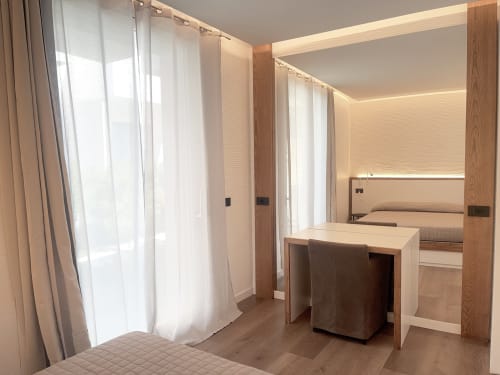 Modern hotel room at Like at Home Palau with desk, vanity mirror, sheer curtains and wooden accents