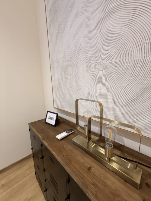Détail d'une chambre d'hôtel moderne à Le Montreal B&B avec bureau en bois, lampe en laiton et artwork circulaire abstrait