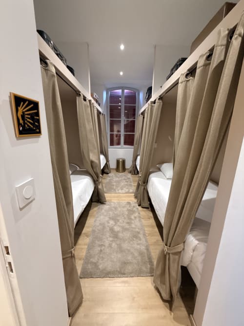 Chambre dortoir moderne du Le Montreal B&B à Montréal du Gers avec quatre lits à rideaux et vue sur la ville