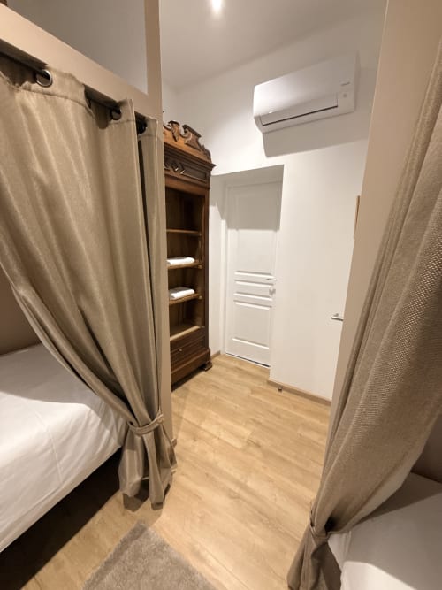 Chambre moderne à la pension Le Montreal à Montréal du Gers avec lits jumeaux, étagère en bois et porte blanche