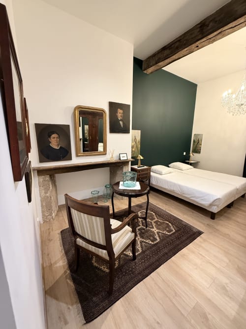 Chambre élégante au gîte Le Montreal avec mur d'accent vert, foyer, portraits d'époque, lit blanc et lustre