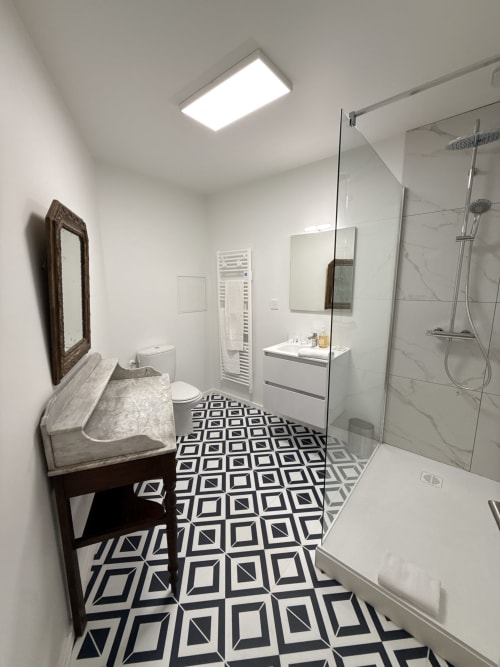 Salle de bain moderne à la Maison d'hôtes Le Montreal à Montréal du Gers avec carrelage géométrique, douche ouverte et vasque en marbre