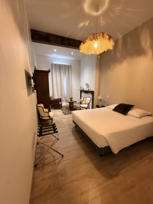 Chambre élégante au Le Montreal B&B à Montréal du Gers avec lit queen-size, luminaire suspendu en fibres tressées et coin détente