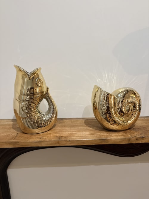 Sculptures décoratives dorées de hibou et d'ammonite sur étagère en bois au gîte Le Montreal à Montréal du Gers