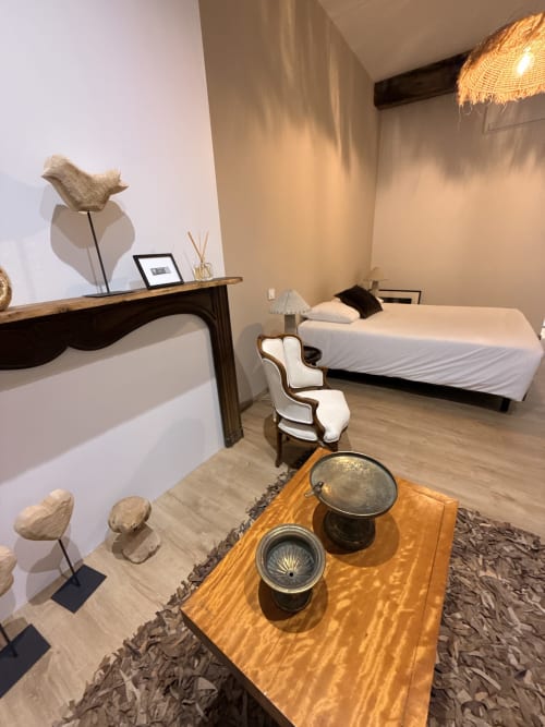Chambre du gîte Montreal BnB avec lit, bureau, sculptures décoratives et table en bois à Montréal du Gers