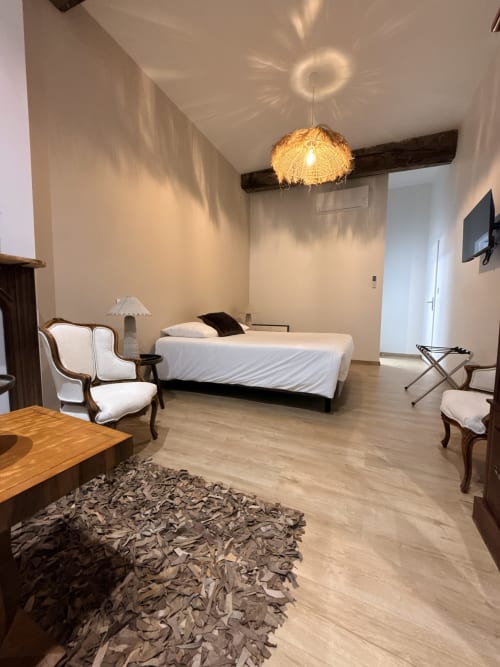 Chambre élégante du Gîte Le Montreal à Montréal du Gers : lit queen-size, poutres en bois, suspension en osier et coin détente.