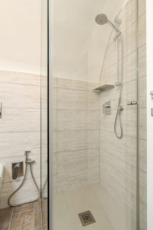 Douche à l'italienne moderne avec carrelage effet marbre, pomme de douche pluie et banc intégré à l'appartement Talking Stones