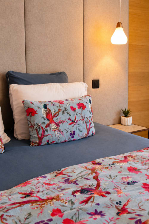 Chambre moderne à Au Pied Des Oliviers avec literie florale, suspension et mur d'accent en bois à Calenzana
