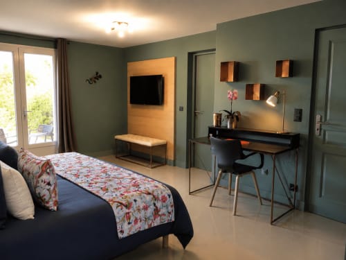 Chambre moderne à Au Pied Des Oliviers, Calenzana avec murs couleur sage, bureau, télévision, étagères en bois et vue sur le jardin