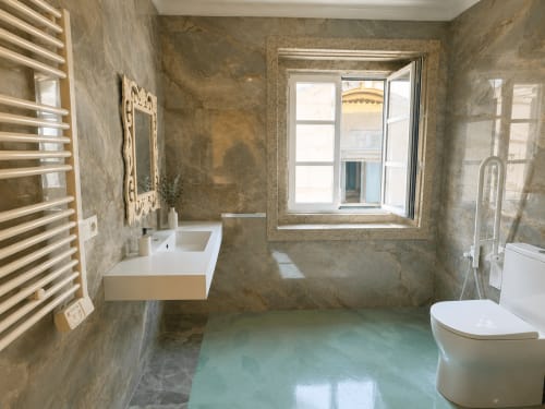 Baño moderno en apartamento Boquiera, Baiona con suelo turquesa, lavabo mural, inodoro, toallero calefactor y ventana