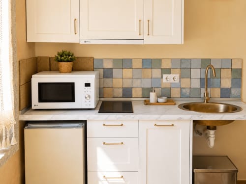 Moderno kitchenette en apartamento Boquiera, Baiona: muebles blancos, azulejos, microondas, lavavajillas y pileta redonda