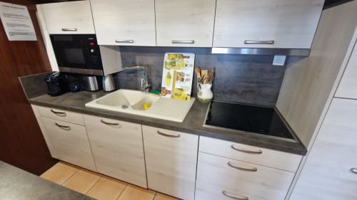Cuisine moderne avec armoires blanches, plan de travail foncé, évier et plaque à induction dans un appartement à Saint-Cyr-sur-Mer