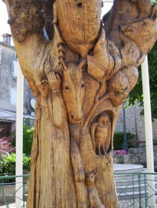 Wooden carved sculpture with figures at Hôtel Du Rocher in Le Caylar, France