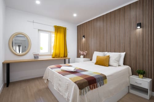 Quarto moderno no RB Algarve TOM Vilamoura com cama branca, detalhes amarelos, parede com revestimento em madeira e penteadeira com espelho.