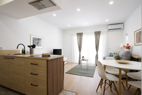 Apartamento moderno em open-plan no RB Algarve Vilamoura com ilha de cozinha em madeira, mesa de jantar e zona de dormir com vista para piscina