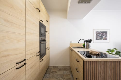 Cozinha moderna no apartamento RB Algarve Vilamoura com móveis em madeira clara, eletrodomésticos em aço inoxidável e ilha