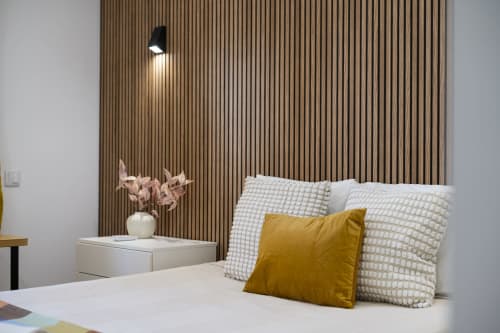 Quarto moderno no RB Algarve Vilamoura com cama, almofada amarela, cabeceira texturizada e luminária de parede