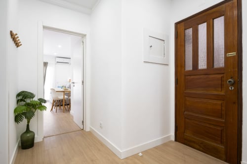 Entrada do corredor do apartamento RB Algarve Vilamoura com porta de madeira, planta verde e acesso às áreas de estar