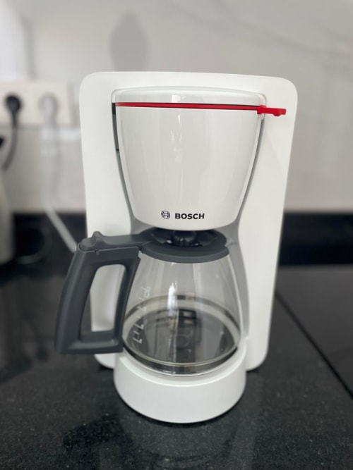Cafeteira Bosch branca com jarra de vidro e alça vermelha no apartamento MedSal Residence