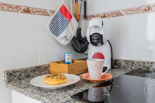 Pequeña cocina en Haus Holiday Homes con cafetera, taza, plato de pastelería y decoración náutica en San Pedro del Pinatar