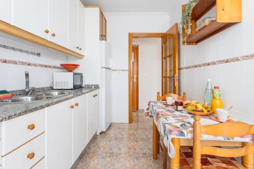 Cocina y comedor modernos en el apartamento Belchi Beach de San Pedro del Pinatar con muebles de madera, encimeras de granito y