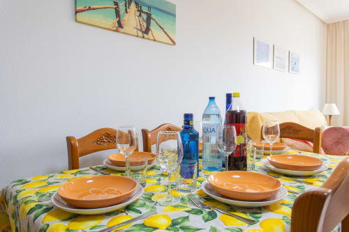 Mesa de comedor preparada para cenar en Haus Holiday Homes, San Pedro del Pinatar, con mantel estampado de limones y sillas de madera