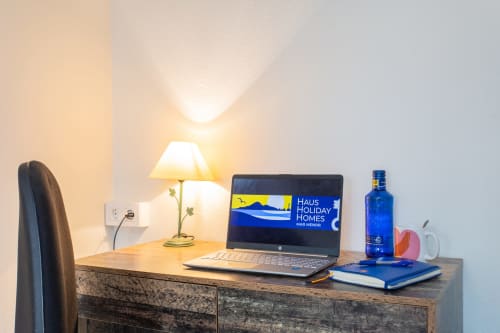 Espacio de trabajo en Haus Holiday Homes con portátil, lámpara, botella azul y libreta en apartamento de San Pedro del Pinatar