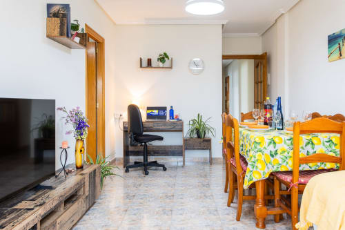Sala de estar abierta en apartamento Belchi Beach, San Pedro del Pinatar, con mesa de comedor, escritorio de trabajo, TV y acabados en madera