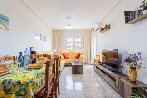 Apartamento diáfano y luminoso en San Pedro del Pinatar con sofá amarillo, mesa de comedor con mantel de limón, zona de TV y