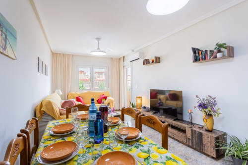 Comedor y sala moderna con mesa amarilla, sillas de madera, TV y balcón amueblado en Haus Holiday Homes