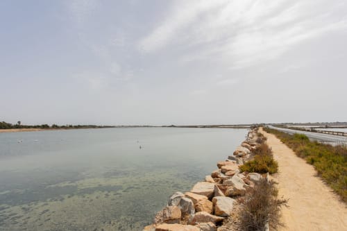 Dique rocoso en las salinas de San Pedro del Pinatar con aguas turquesas tranquilas y paseo arenoso