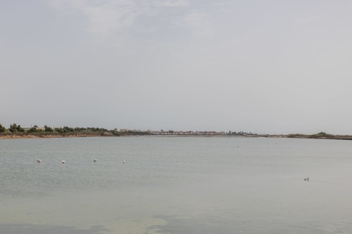 Vista tranquila de la laguna salada de Playa Belchi, San Pedro del Pinatar con litoral distante y veleros