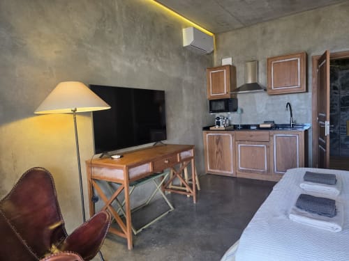 Suite moderna en Les Terrasses Les Suites de Calheta con kitchenette, cama, escritorio, TV e iluminación cálida